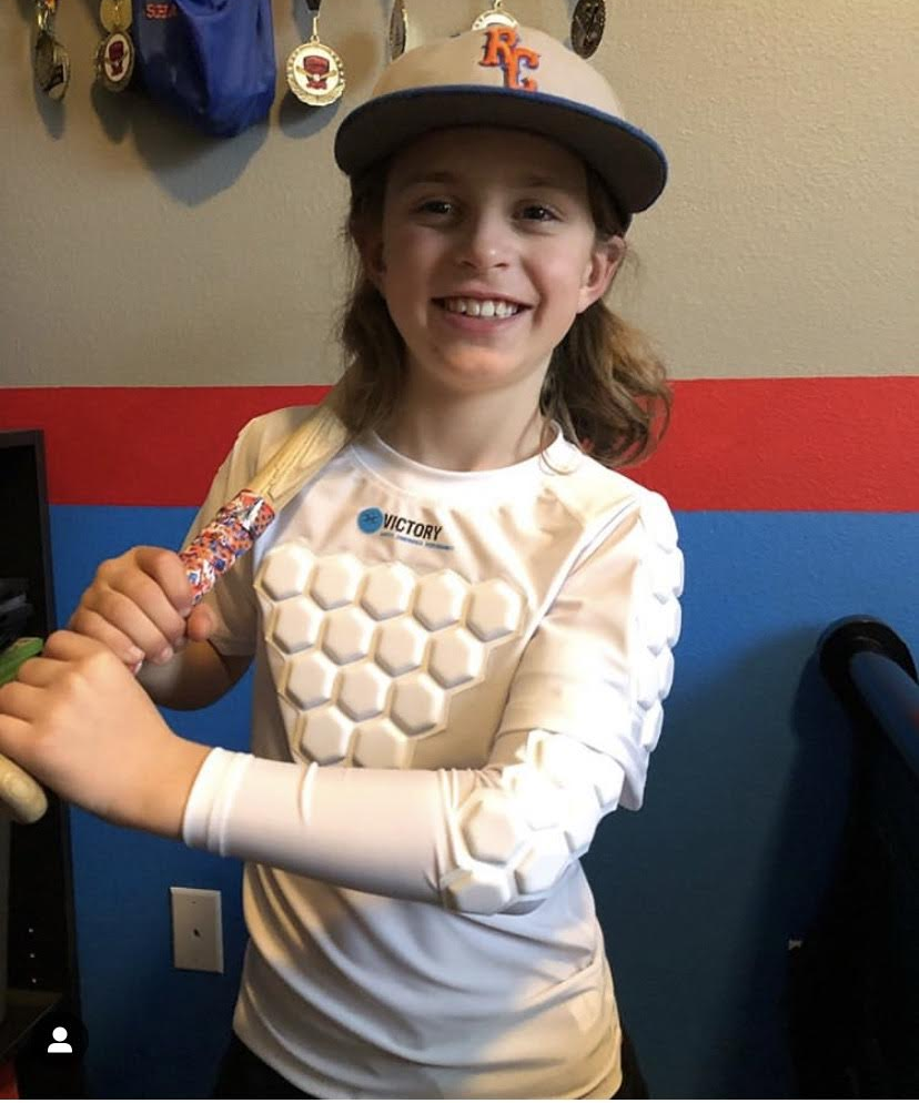 Youth baseball player with baseball and softball protective padded elbow sleeve