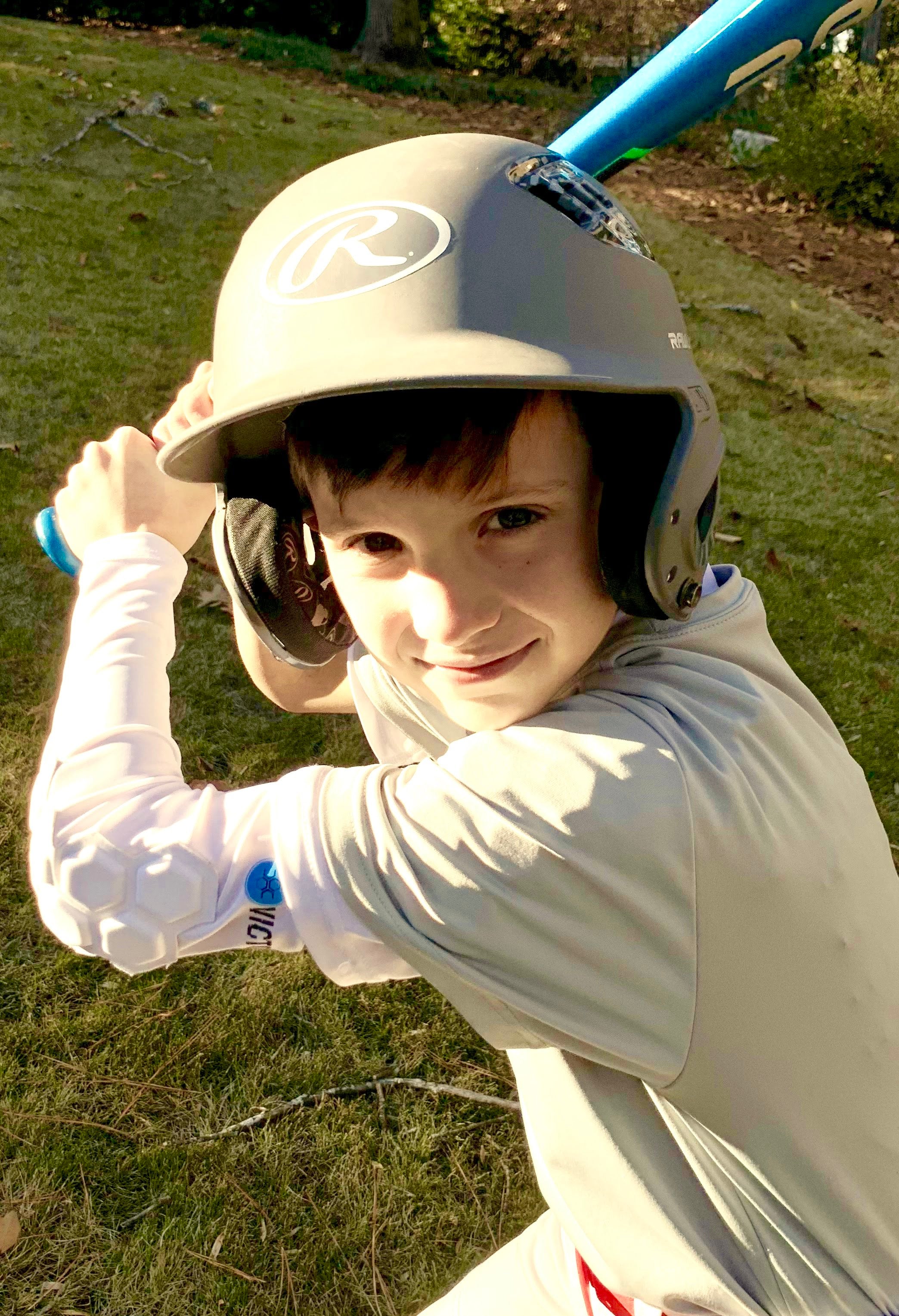 Youth baseball player with baseball and softball protective padded elbow sleeve