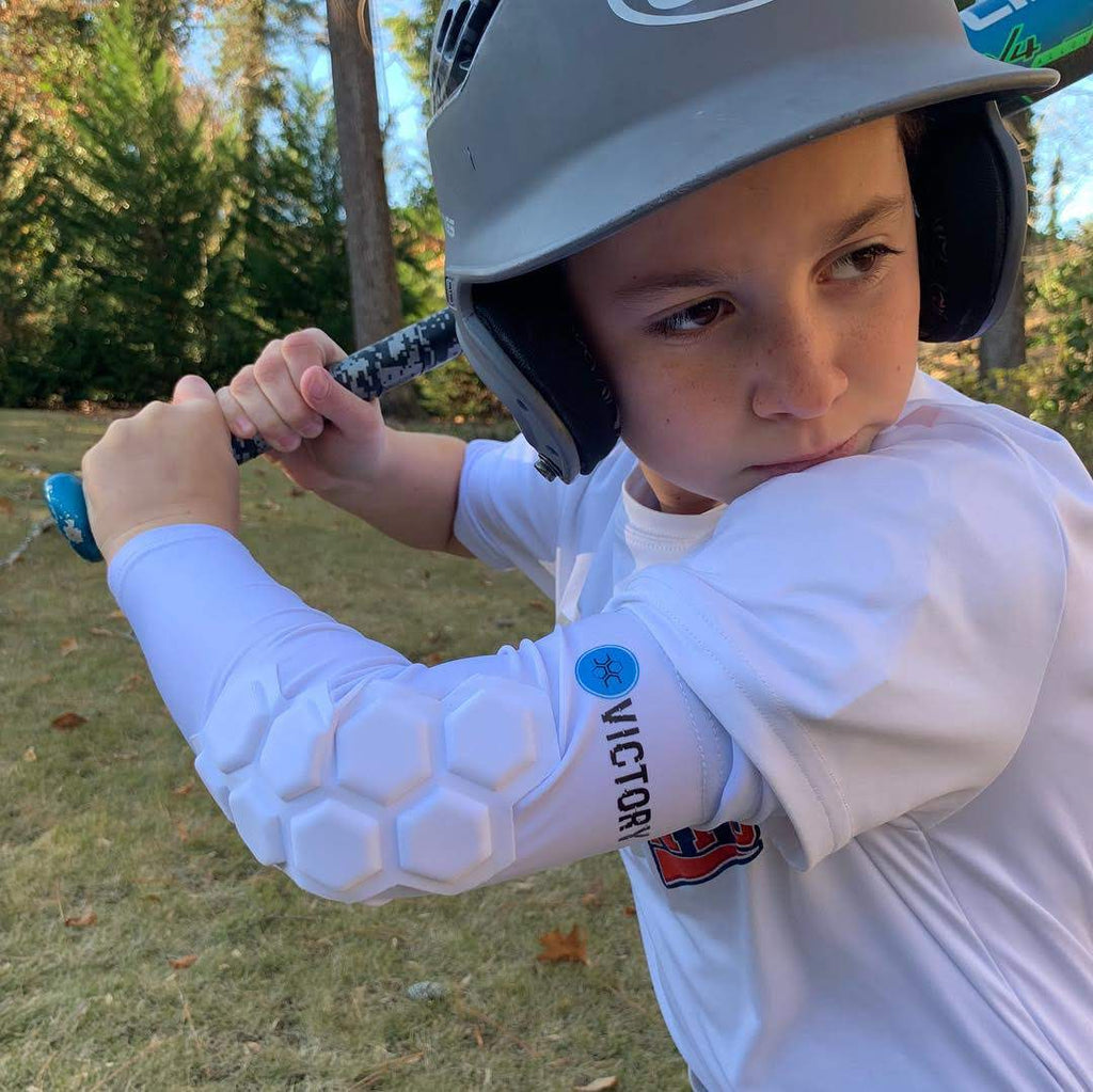 Youth baseball player with baseball and softball protective padded elbow sleeve