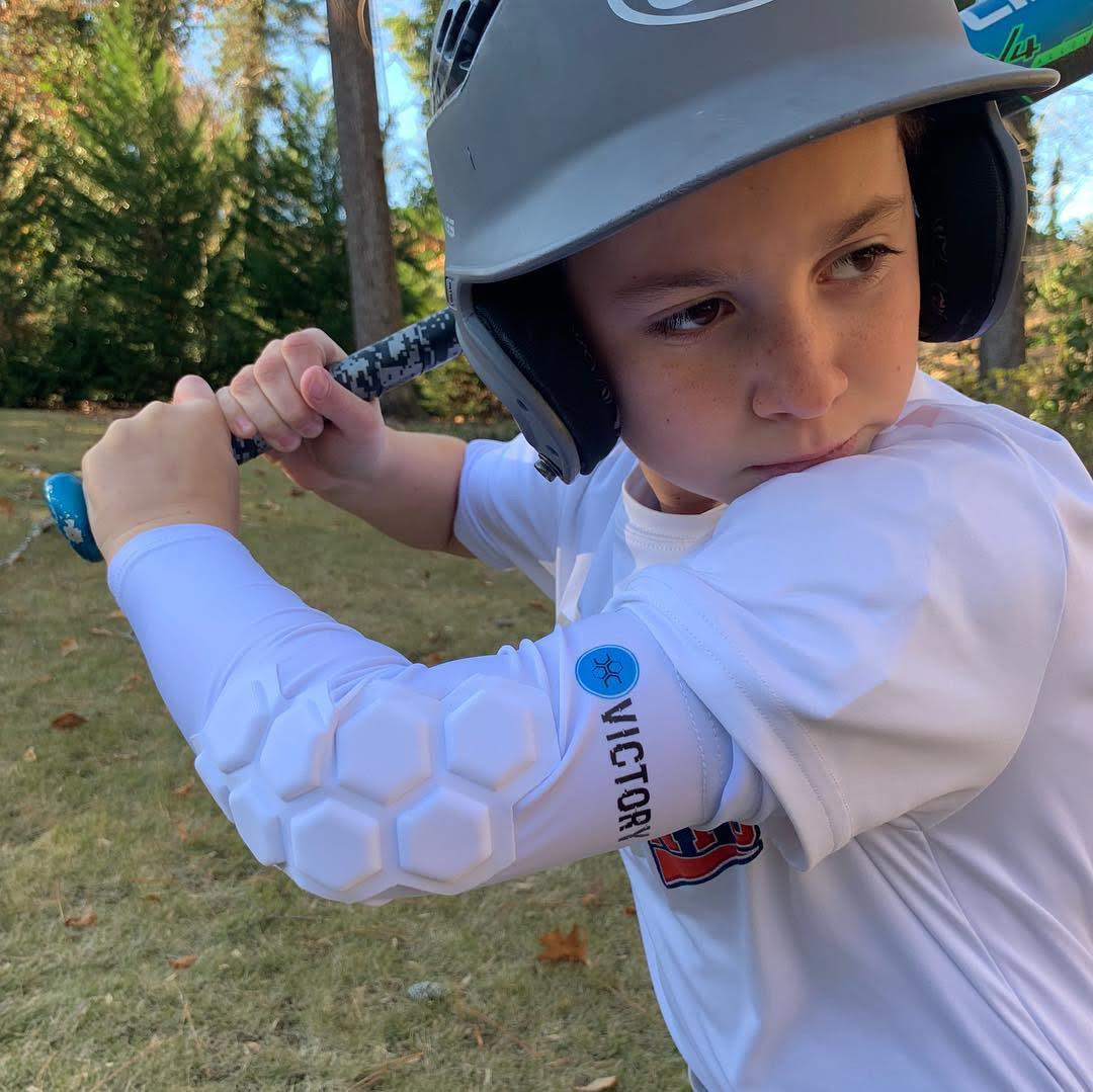 Youth baseball player with baseball and softball protective padded elbow sleeve