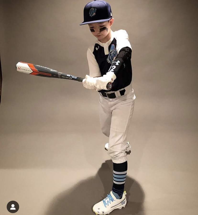 Youth baseball player with baseball and softball protective padded elbow sleeve